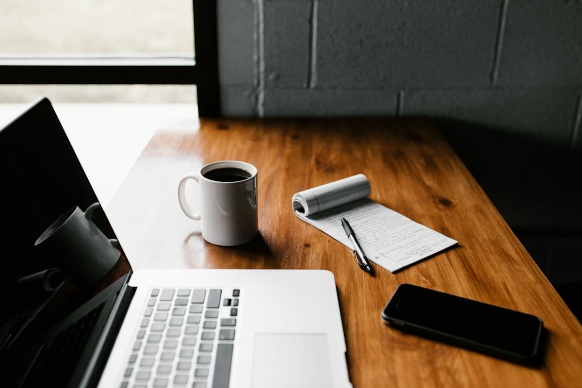 Modern creative writing desk with laptop, draft notes, coffee, and typography journal