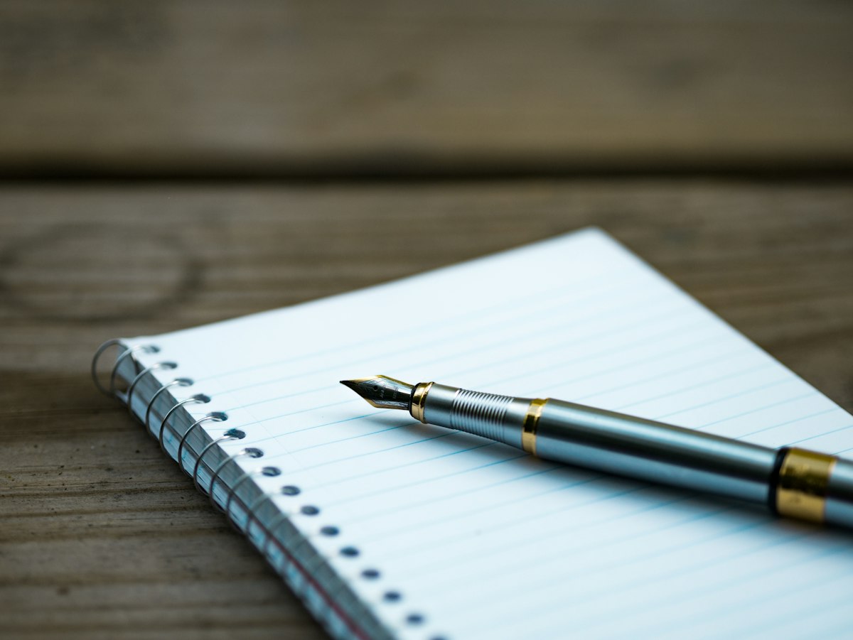 Author reviewing printed draft manuscript pages with notes and fountain pen
