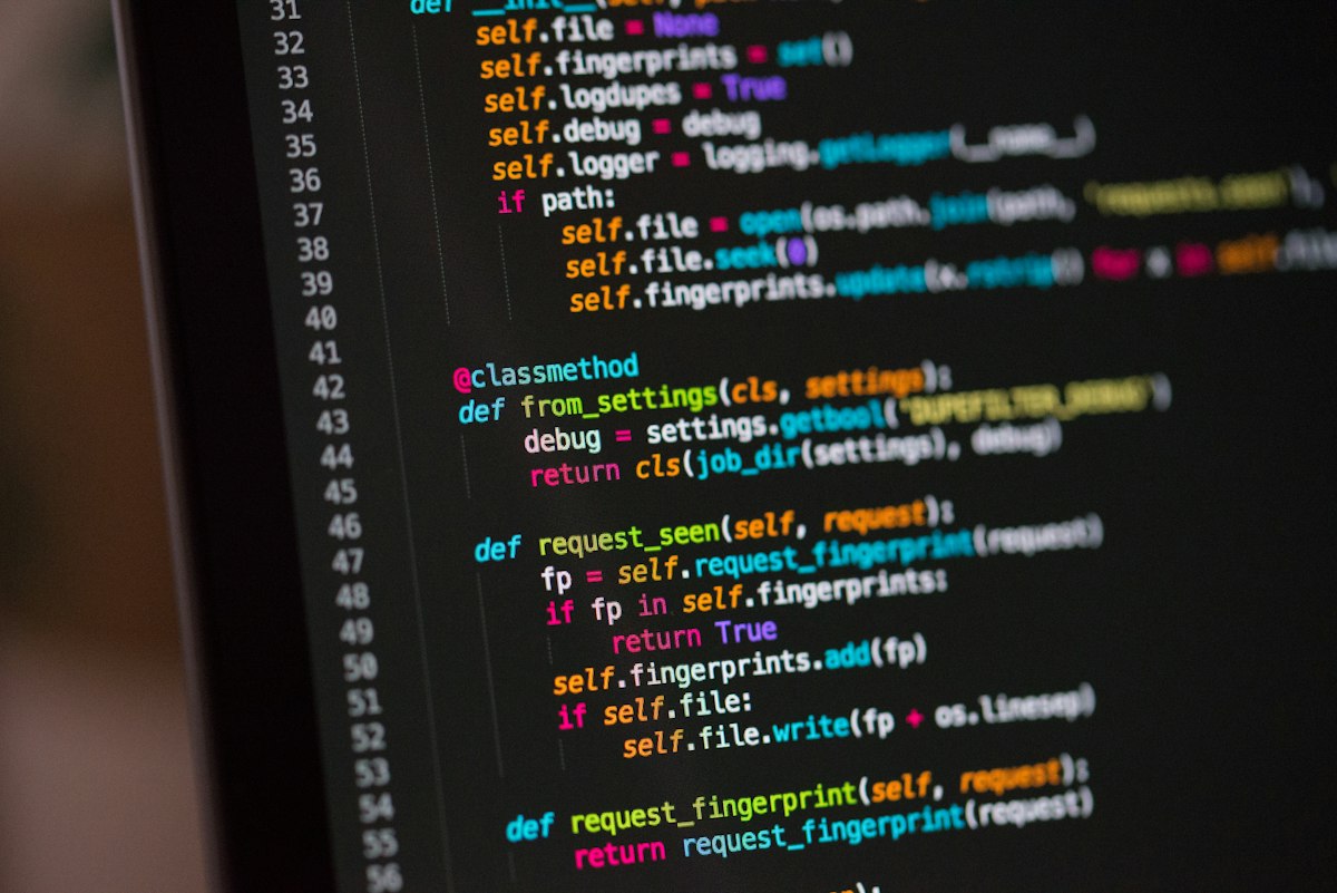 Multiple monitors displaying syntax highlighted code in an engineering workspace